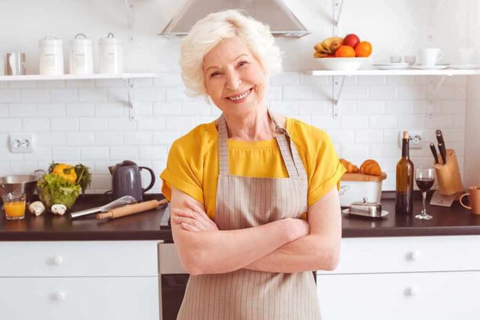Smiling older woman in apron standing in a bright kitchen