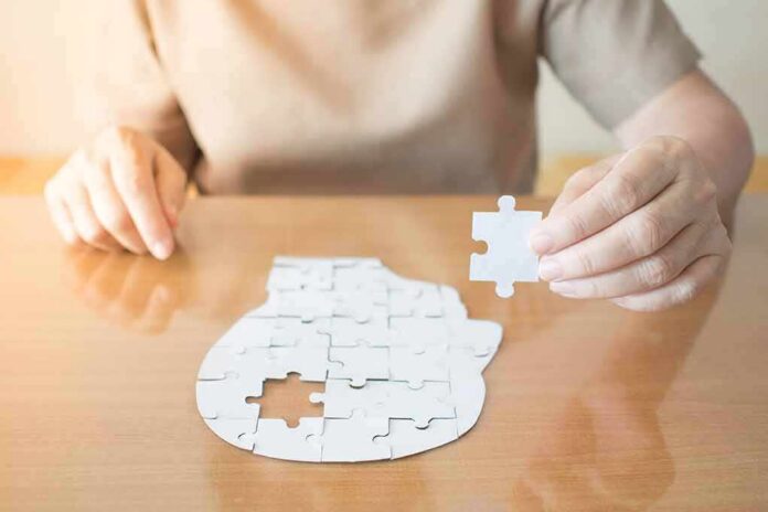 shutterstock_1136971007 Person holding puzzle piece over head-shaped jigsaw on table