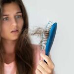 Woman holding a hairbrush with clumps of hair
