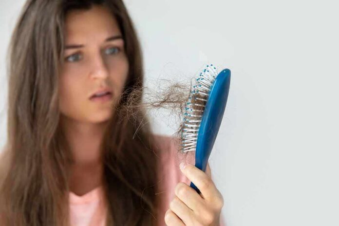 Woman holding a hairbrush with clumps of hair
