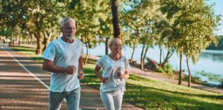 Two adults jogging on a tree-lined lakeside path