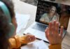 Student in headphones waving at a person on a laptop video call