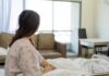 Cancer Survivors’ Hidden Crisis Patient sitting on a hospital bed looking toward a bright window
