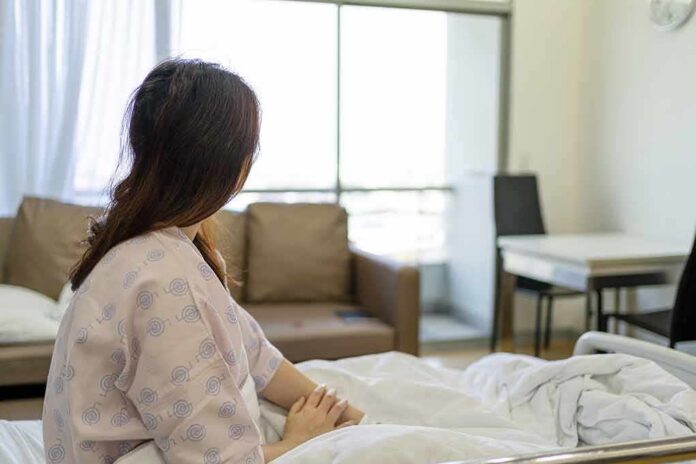 shutterstock_1924099922 Patient sitting on a hospital bed looking toward a bright window