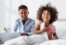two smiling children sitting on a bed