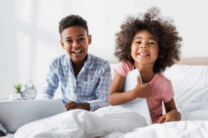 two smiling children sitting on a bed
