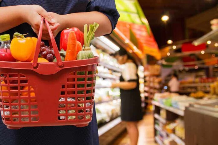 shutterstock_233691502 Person holding a basket filled with colorful vegetables in a supermarket