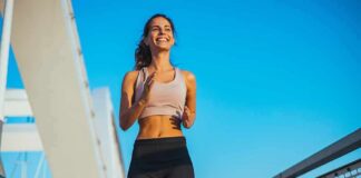Smiling woman jogging on a bridge under a clear blue sky