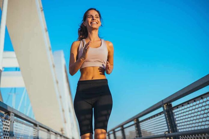 Smiling woman jogging on a bridge under a clear blue sky