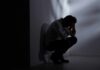 Silhouetted person crouching in a dimly lit corner