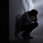 Silhouetted person crouching in a dimly lit corner