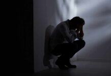 Silhouetted person crouching in a dimly lit corner